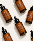 Luxury flat lay of Skin Cosmetica Luxe Vitamin C Serum bottles on a soft bone background, showcasing a brightening vitamin C serum for radiant, hydrated skin.