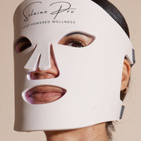 Model relaxing while using the Solaine Pro LED face mask, demonstrating its soothing and therapeutic benefits for skincare