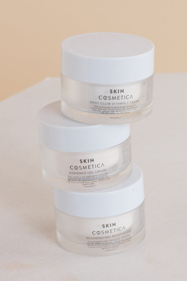 Three moisturizers from Skin Cosmetica: Rejuvenating Moisturizer, Daily Glow Vitamin C Moisturizer, and Radiance Gel Cream, displayed together on a marble countertop