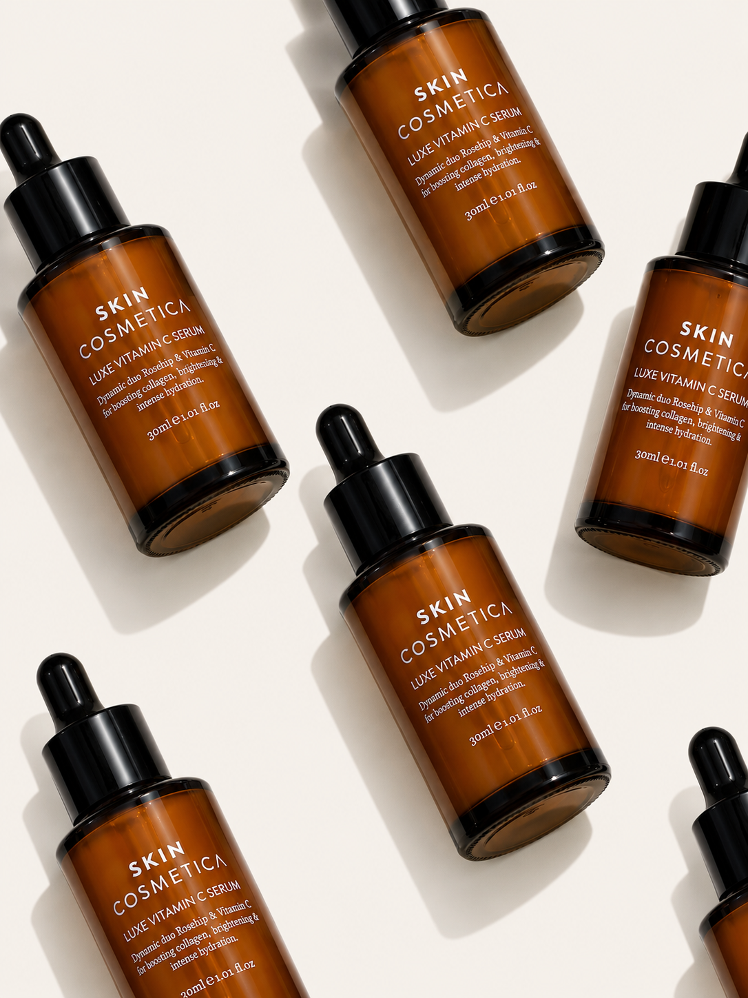 Luxury flat lay of Skin Cosmetica Luxe Vitamin C Serum bottles on a soft bone background, showcasing a brightening vitamin C serum for radiant, hydrated skin.